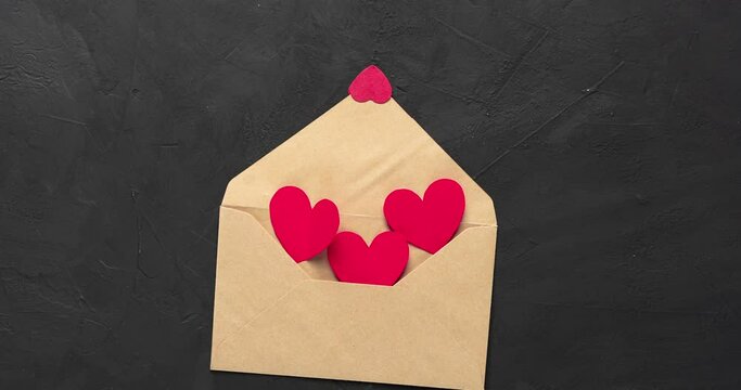 Paper hearts fly out of an envelope on a black background. Valentine's day concept.
