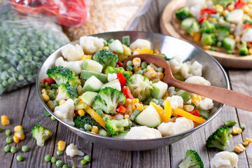 Mix of frozen vegetables in a bowl on wooden table