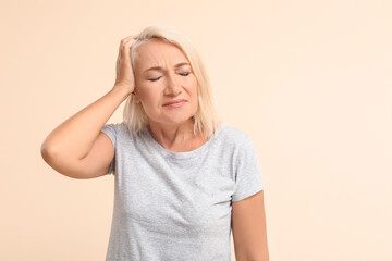 Stressed mature woman suffering from headache on color background