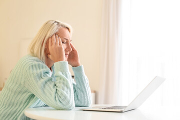 Stressed mature woman suffering from headache at home