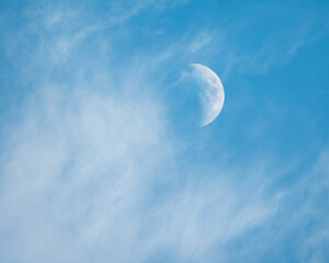 Naklejka na ściany i meble Moon among white clouds in blue sky