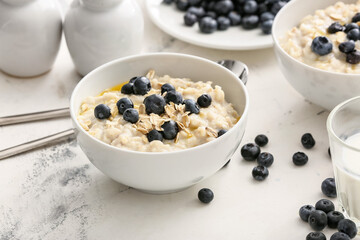 Bowls with tasty oatmeal and blueberry on table