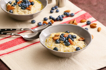 Bowls with tasty oatmeal and blueberry on table