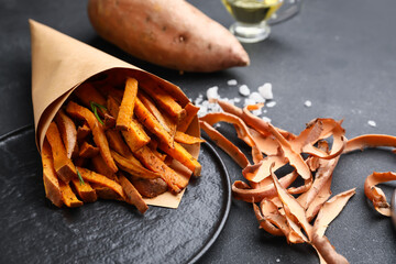 Paper bag with tasty cooked sweet potato on dark background