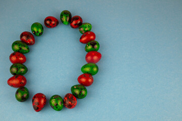 Multicolored quail eggs green and red on a blue background with place for text. Happy Easter postcard. Easter eggs copy space.