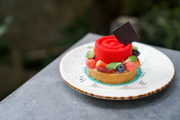 Flower Fruit Tart. A strawberry mousse cake topped with berries fruit, strawberry, blueberry and raspberry on table at garden.