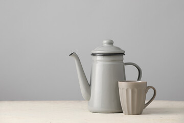 Teapot and cup on table against grey background