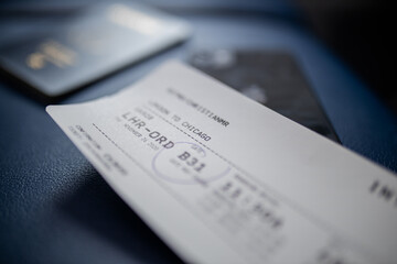 Airplane ticket and smartphone above a dark blue seat