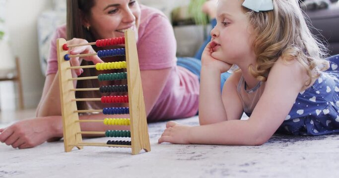 Caucasian mother and daughter having fun using abacus