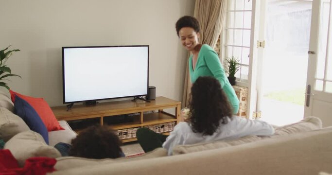 Mixed race lesbian couple and daughter watching tv sitting on couch