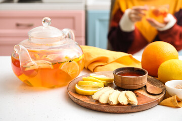 Teapot and board with lemon, ginger and honey on table