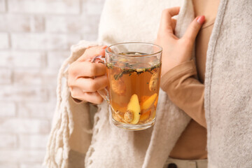 Woman holding cup of hot ginger tea, closeup