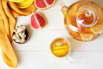 Teapot and cup of healthy drink with lemon and ginger on table