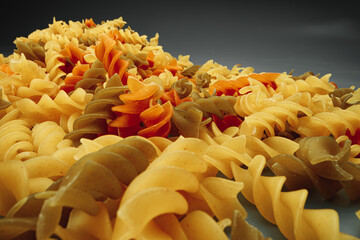 Uncooked pasta swirls on dark background macro