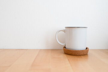 White hot coffee cup on wooden table and white wall with copy space.
