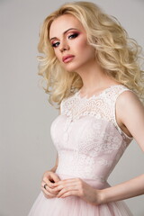 Naklejka premium beautiful blonde girl in a pink wedding dress posing in the studio on a light background