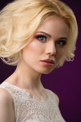 portrait of a beautiful blonde girl in a white wedding dress on a dark background