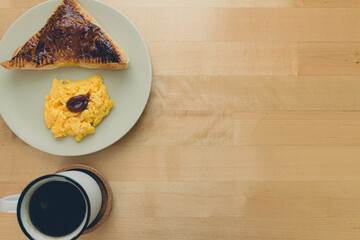 Breakfast set of homemade sandwich pie with scrambled egg and black coffee.
