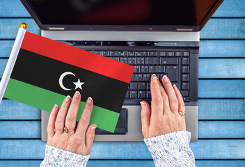 woman hands and flag of Libya on computer, laptop keyboard 