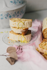 Delicious homemade sponge cake with white chocolate frosting and lemon zest sprinkle, sliced into servings with vintage style crockery. Simple traditional English sweet dish. Home baked dessert.   