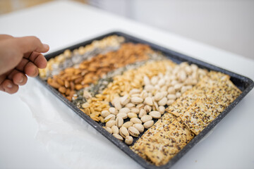 Black tray of nuts and seeds above a white table