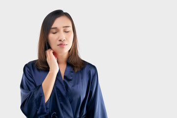 Asian women in the dark blue robe are scratching their necks due to itching on a gray background. The Female has an itching arm. The concept of allergy symptoms and healthcare