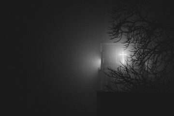 leuchtendes Kreuz am Kirchturm nachts im Nebel