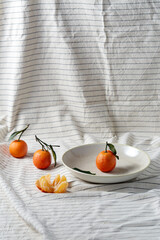 food, healthy eating and fruits concept - close up of mandarins on plate over drapery