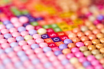 Girl collect diamond painting. Diamond embroidery with a tweezers. Acrylic rhinestones. Close-up,...