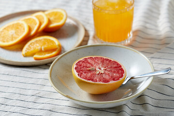 food, healthy eating and fruits concept - still life of grapefruit, sliced orange and glass of juice over drapery