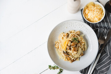 Risotto with porcini mushrooms and parmesan on a light background, copy space