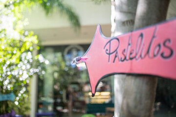 Pink arrow sign for pastries on a tree trunk