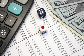 On the document with columns of numbers are playing dice. Dollars and a calculator. The concept of...