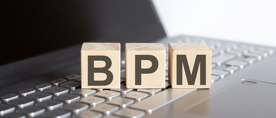 BPM Business Process Management written on a wooden cube on laptop