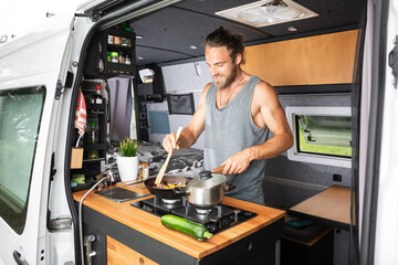 Man cooking on a stove inside his camper van