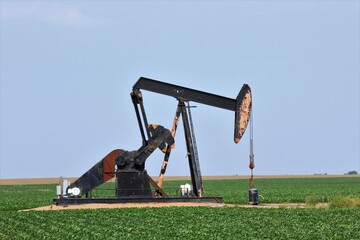 oil pump jack in the field south of Ellsworth Kansas USA in a farm field.
