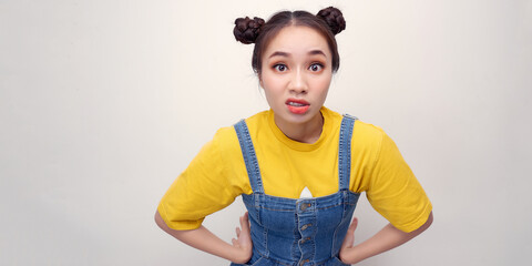 Portrait of serious girl  denim sundress standing with arms akimbo on waist isolated on white wall background.