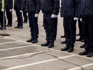 A group of military standing on the parade ground. Side view of police officers or soldiers wearing black uniforms, white gloves and coarse boots.