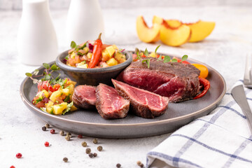 Fried beef steak with peach fruit salsa, tomato and chili.