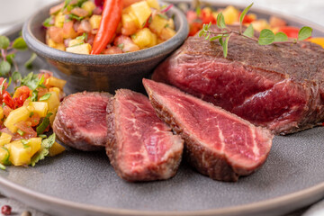 Fried beef steak with peach fruit salsa, tomato and chili.