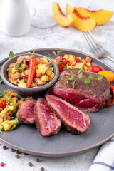 Fried beef steak with peach fruit salsa, tomato and chili.