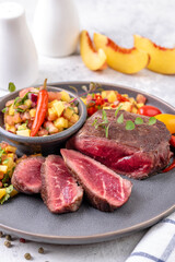 Fried beef steak with peach fruit salsa, tomato and chili.
