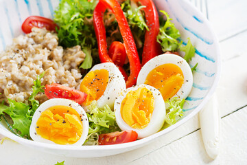 Breakfast oatmeal porridge with green herbs, boiled egg, tomatoes and paprika. Healthy balanced food.