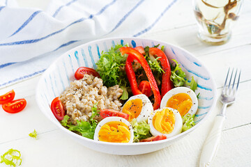 Breakfast oatmeal porridge with green herbs, boiled egg, tomatoes and paprika. Healthy balanced food.