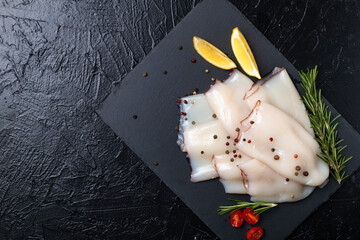 Fresh raw squid fillet with lemons, tomatoes and rosemary.