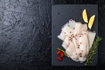 Fresh raw squid fillet with lemons, tomatoes and rosemary.