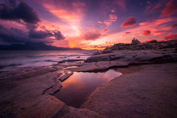 Sunset over tower and rocky coastline of Corsica