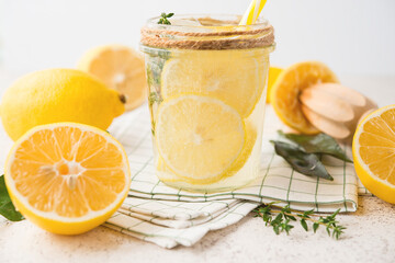 Homemade refreshing lemonade, detox drink with lemon and herbs on a light background