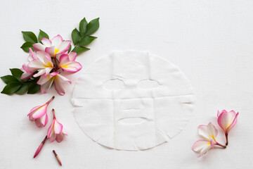 natural aroma sheet mask for skin face from herbal flower pink frangipani essence face mask on arrangement flat lay style background white