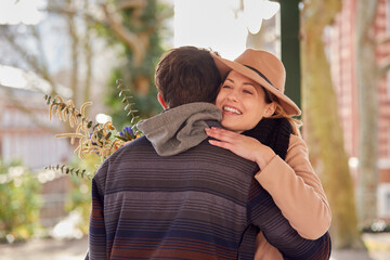 Romantic Man Hugging Young Woman After Giving Her Bouquet Of Flowers As They Meet In City Park